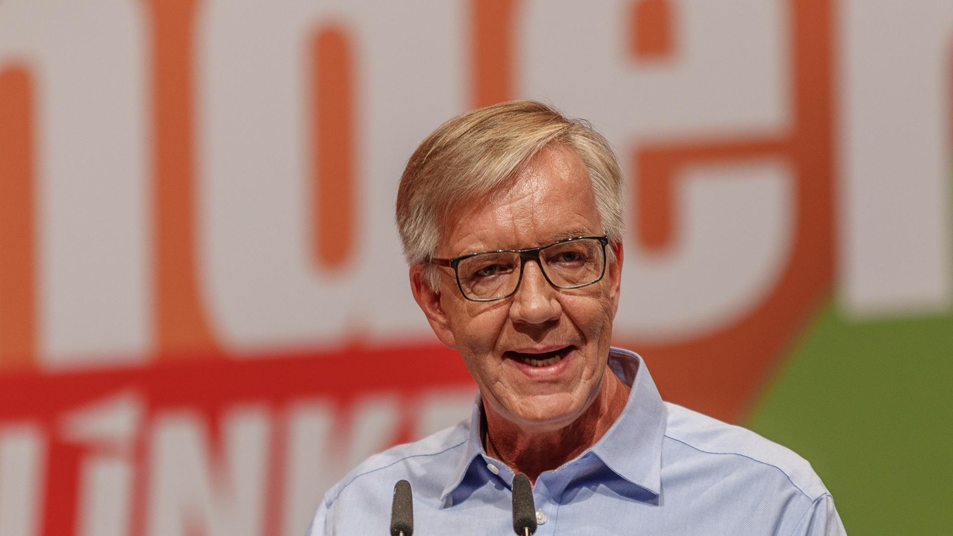Ein Mann steht auf einer Bühne und hält eine Rede. Er trägt ein hellblaues Hemd. Es ist der Linke-Politker Dietmar Bartsch. Ein Mann steht auf einer Bühne und hält eine Rede. Er trägt ein hellblaues Hemd. Es ist der Linke-Politker Dietmar Bartsch.