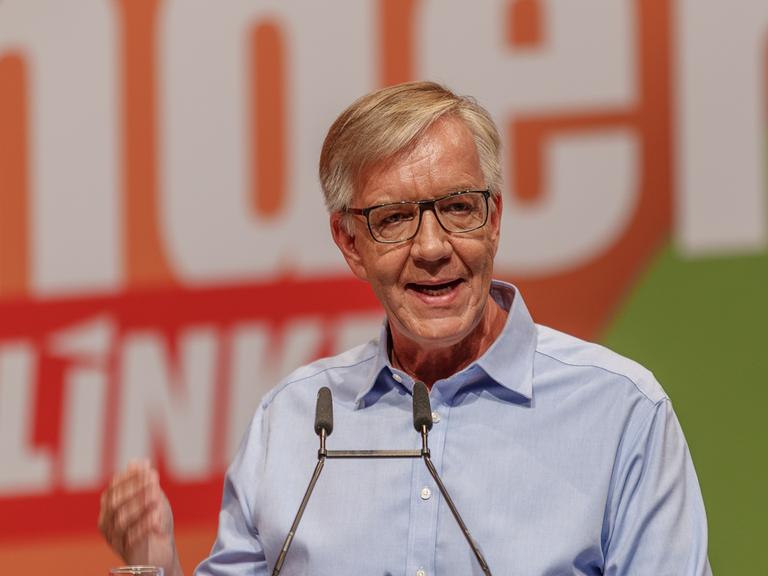 Ein Mann steht auf einer Bühne und hält eine Rede. Er trägt ein hellblaues Hemd. Es ist der Linke-Politker Dietmar Bartsch.