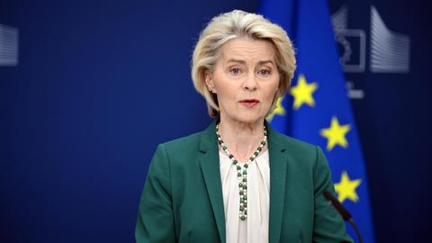 EU-Kommissionspräsidentin Ursula von der Leyen stehend vor einer EU-Fahne 