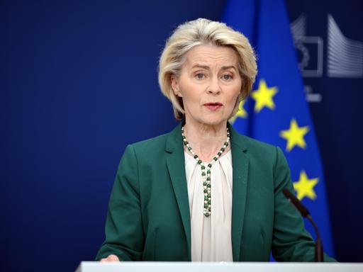 EU-Kommissionspräsidentin Ursula von der Leyen stehend vor einer EU-Fahne 