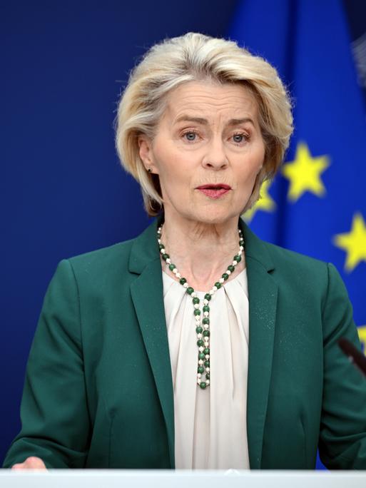 EU-Kommissionspräsidentin Ursula von der Leyen stehend vor einer EU-Fahne 