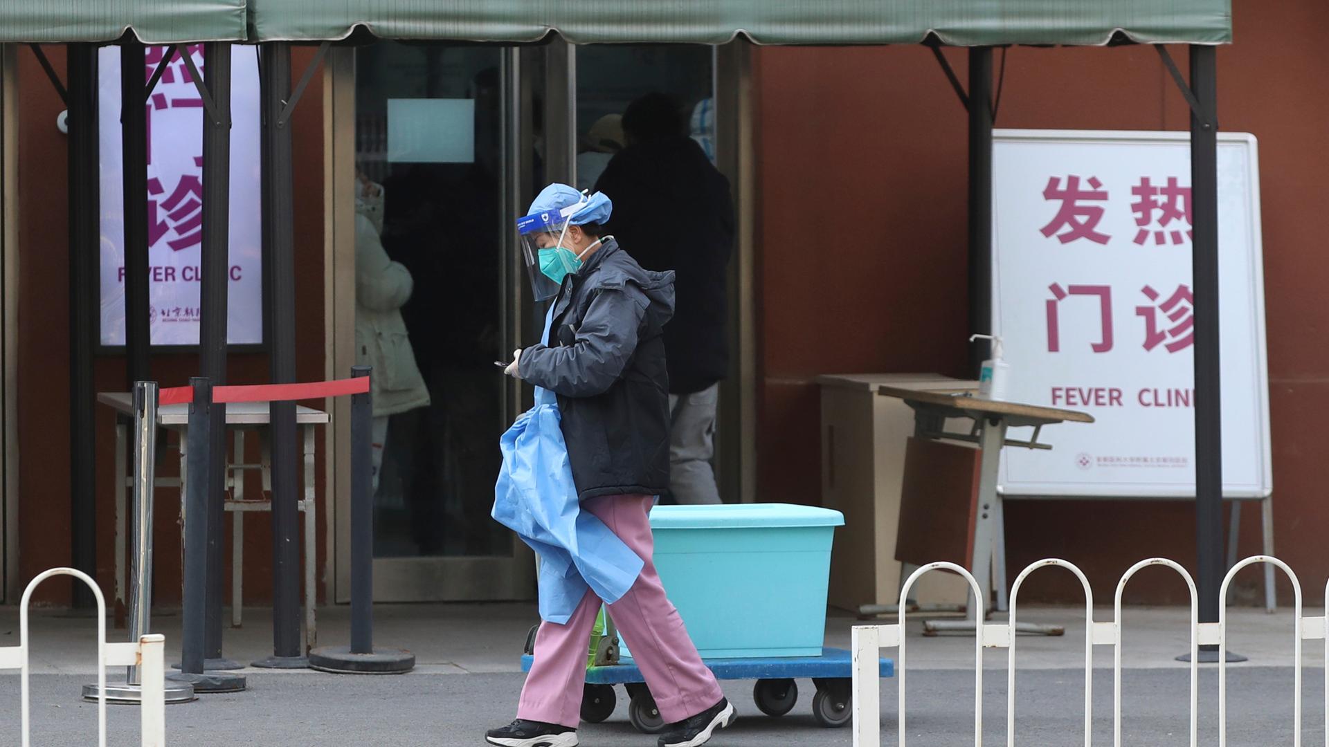 Ein Mann in Schutzkleidung läuft vor einer Spezialklinik für Fieberpatientinnen in Peking vorbei, 15. Dezember 2022. 