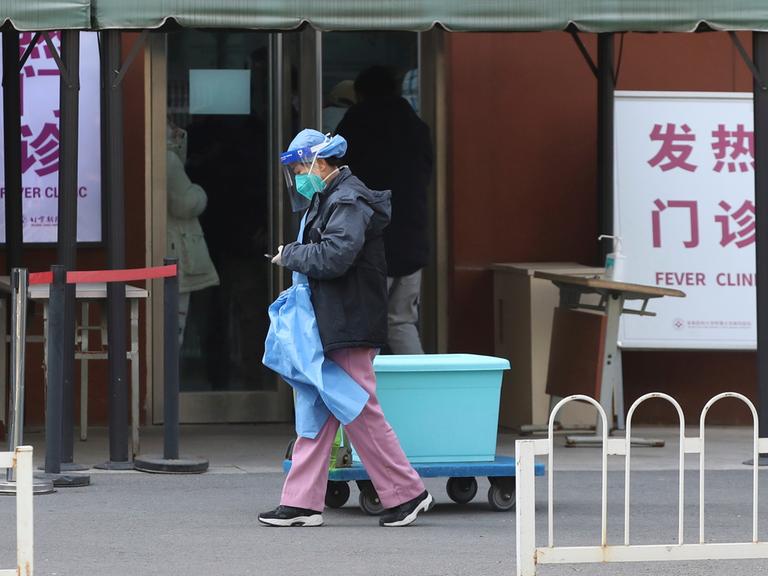 Ein Mann in Schutzkleidung läuft vor einer Spezialklinik für Fieberpatientinnen in Peking vorbei, 15. Dezember 2022. 