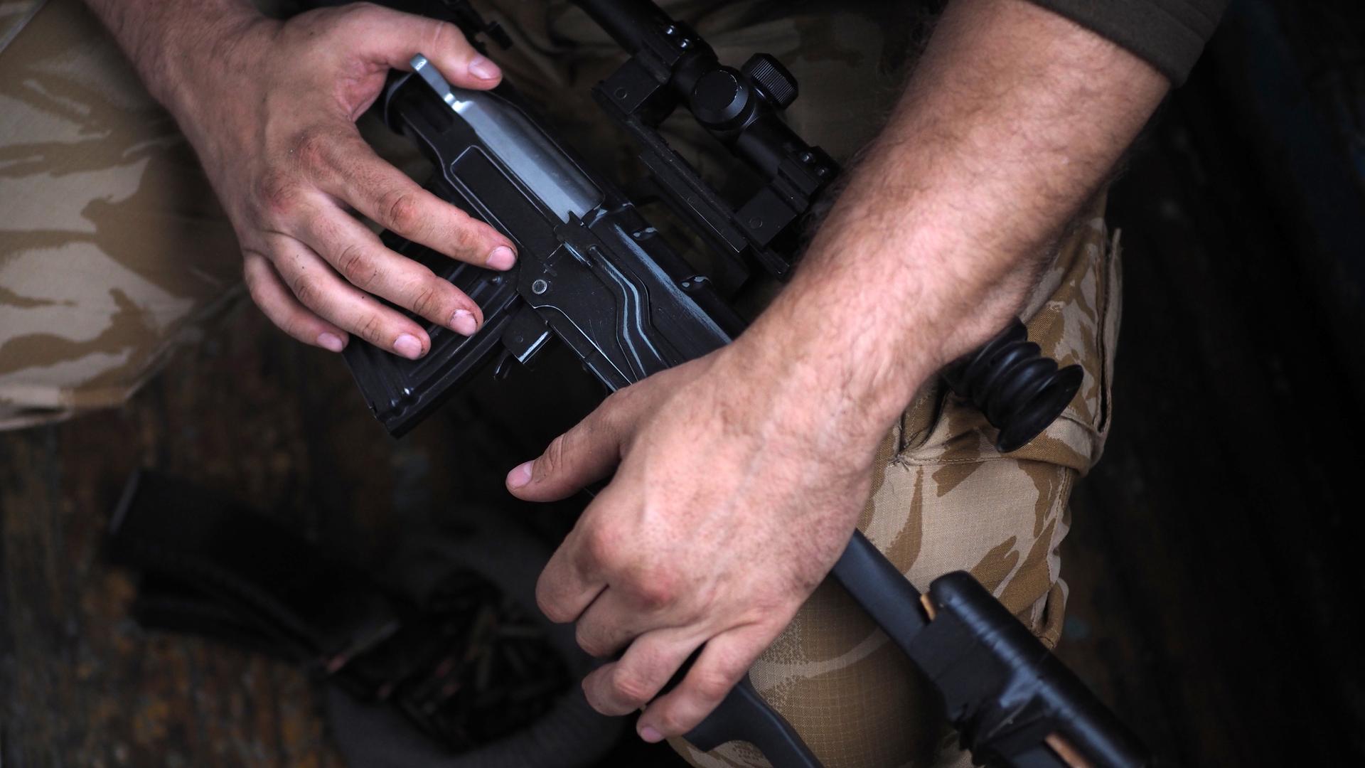 Die Hände eines Soldaten am Gewehr. Close-Up