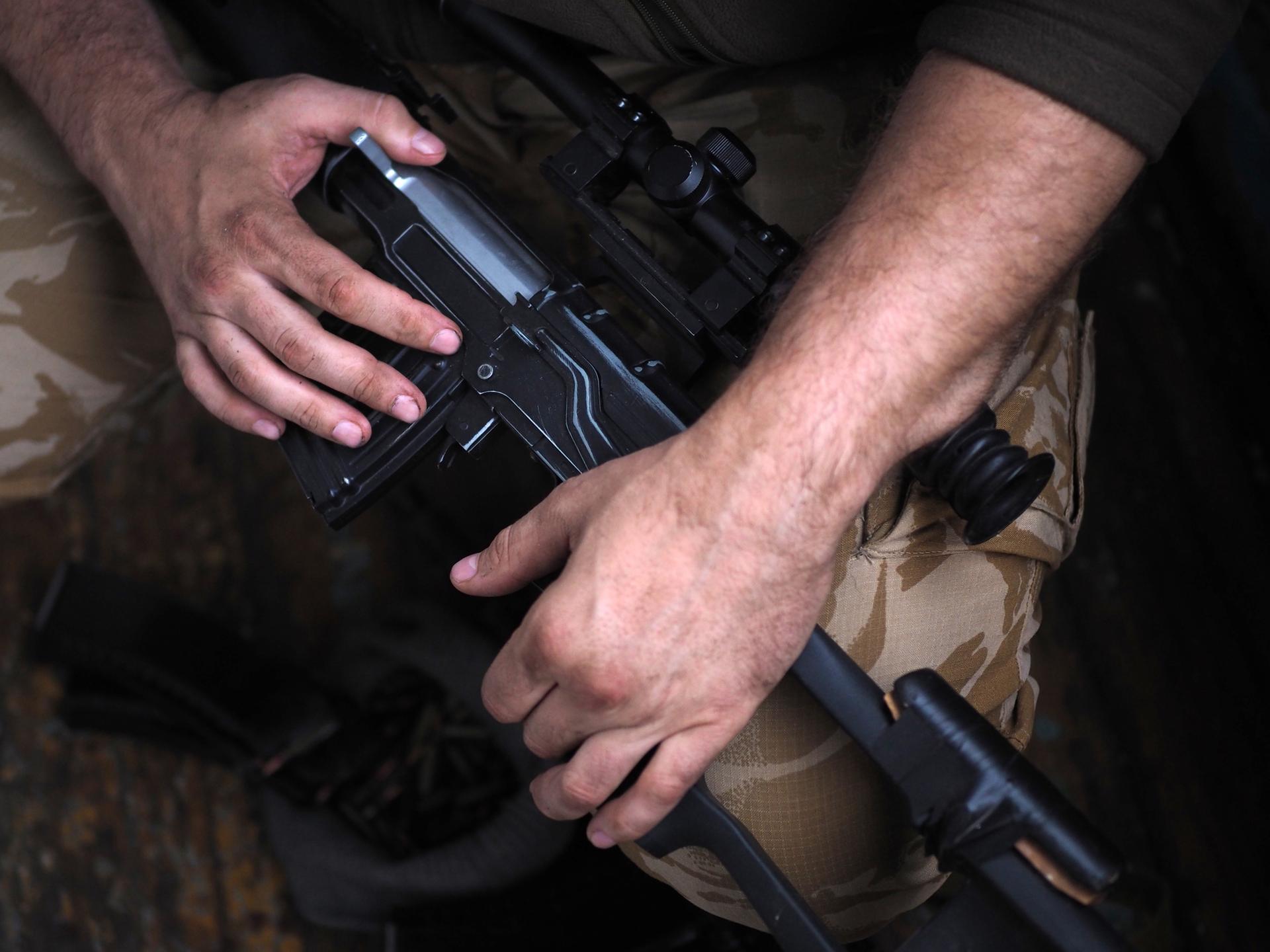 Die Hände eines Soldaten am Gewehr. Close-Up