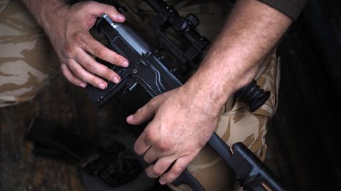 Die Hände eines Soldaten am Gewehr. Close-Up