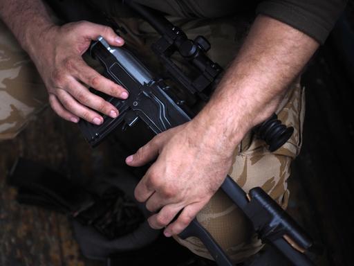 Die Hände eines Soldaten am Gewehr. Close-Up