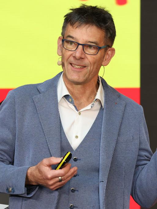 Der Biologe Martin Wikelski steht auf einer Bühne und spricht gestikulierend. 