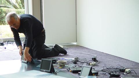 Ein Mann kniet auf dem Boden und verkabelt Monitore, Lautsprecher und andere Teile