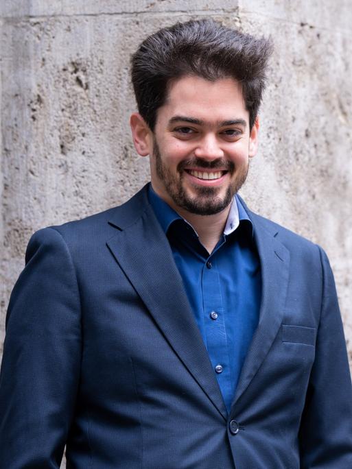 Lahav Shani, zukünftiger Chefdirigent der Münchner Philharmoniker, lehnt an einer Wand.
