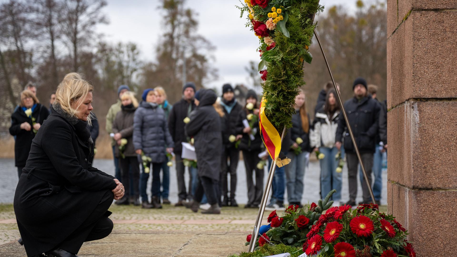 Bundesinnenministerin Nancy Fauser (SPD) kniet bei der Kranzniederlegung am Denkmal "Tragende" bei der Gedenkveranstaltung in der Mahn- und Gedenkstätte Ravensbrück