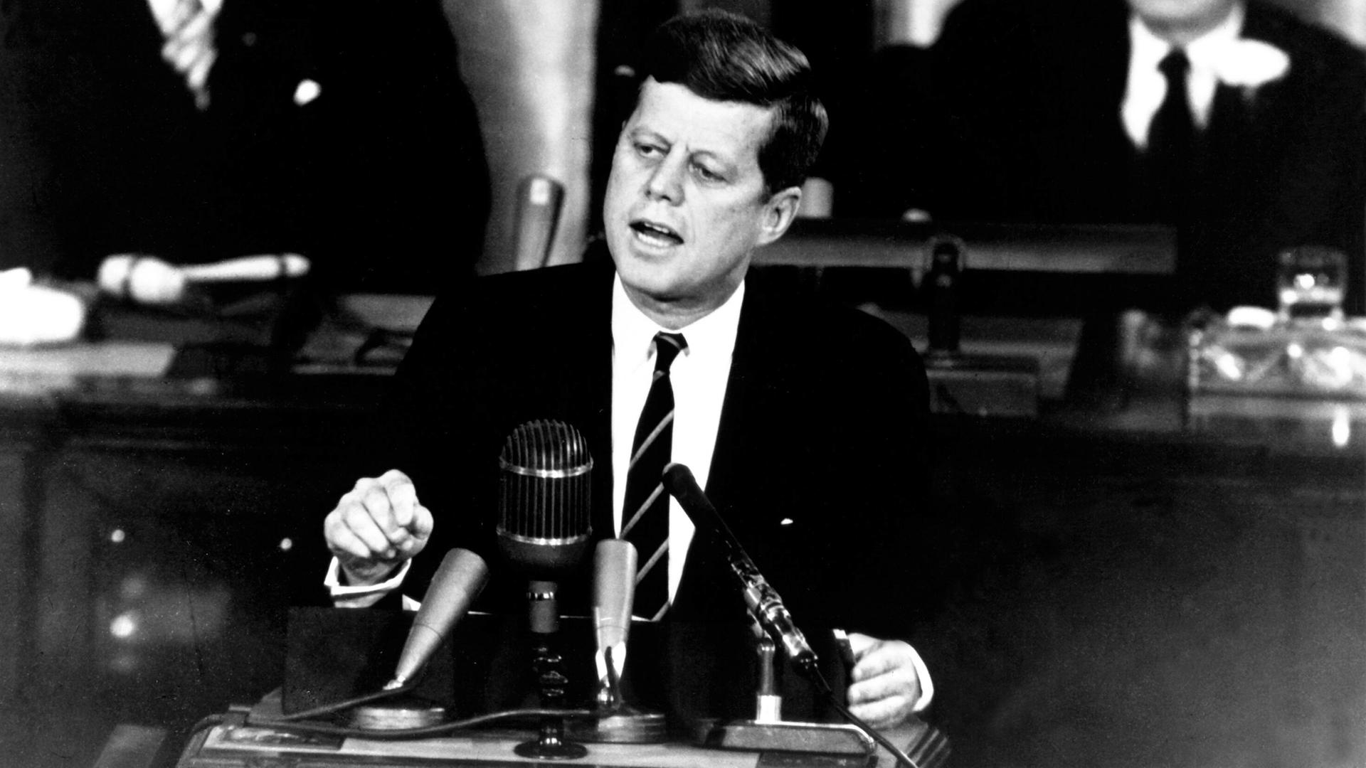 Historisches Schwarzweiß-Foto von John F. Kennedy, der eine Rede hält.