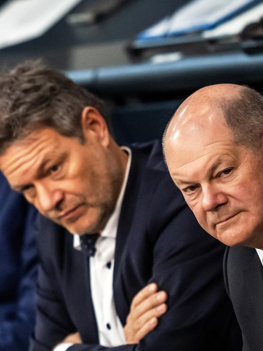 Bundeskanzler Olaf Scholz (SPD, r), verfolgt neben Robert Habeck (Bündnis 90/Die Grünen, M), Bundesminister für Wirtschaft und Klimaschutz, und Christian Lindner (FDP), Bundesminister der Finanzen, die Debatte nach einer Regierungserklärung zur Haushaltslage im Bundestag.
