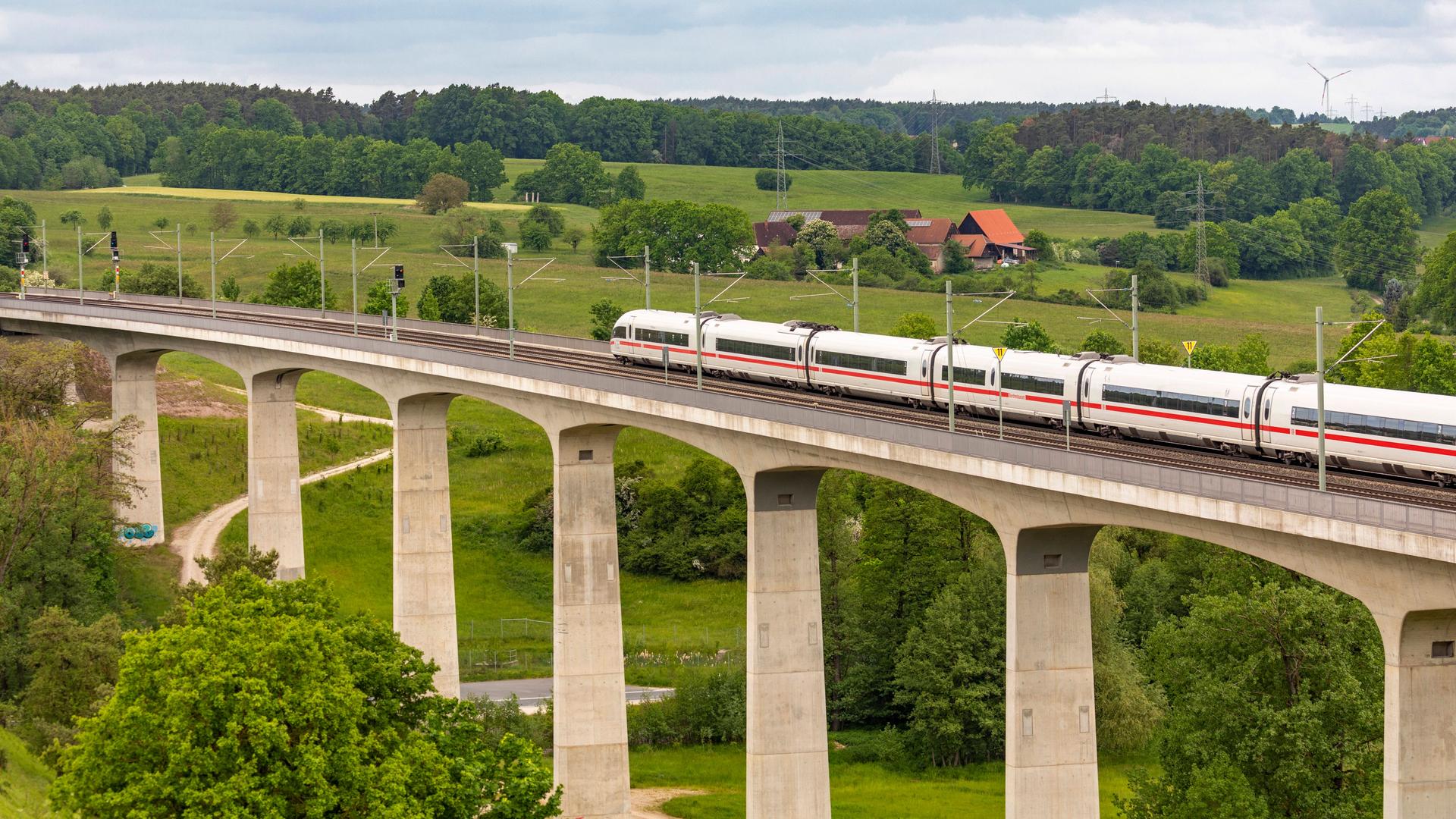 Bahnverkehr auf der Schnellfahrstrecke Nürnberg - Würzburg: Ein ICE fährt über eine hohe Brücke, eingerahmt von der Landschaft.