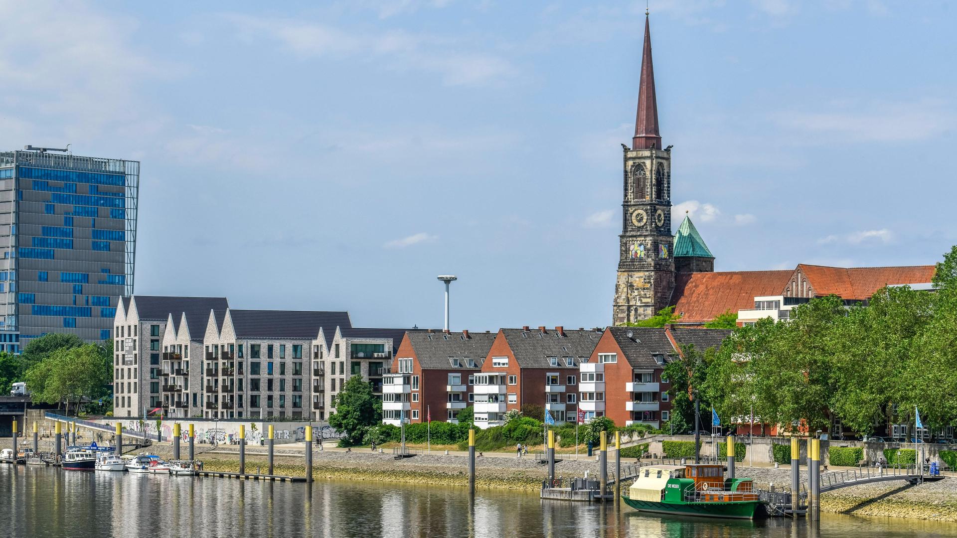 Die Weserpromenade in Bremen mit der Stephanikirche und einem Boot im Vordergrund.