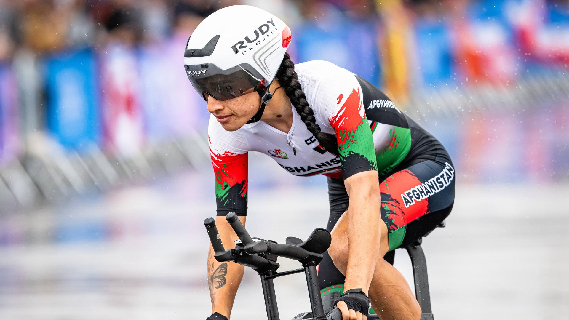 Die afghanische Radsportlerin Hashimi Yulduz fährt bei den Olympischen Spielen in Paris 2024 durch den Regen