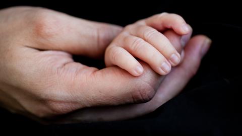 Eine grosse Hand hält eine Kinderhand.