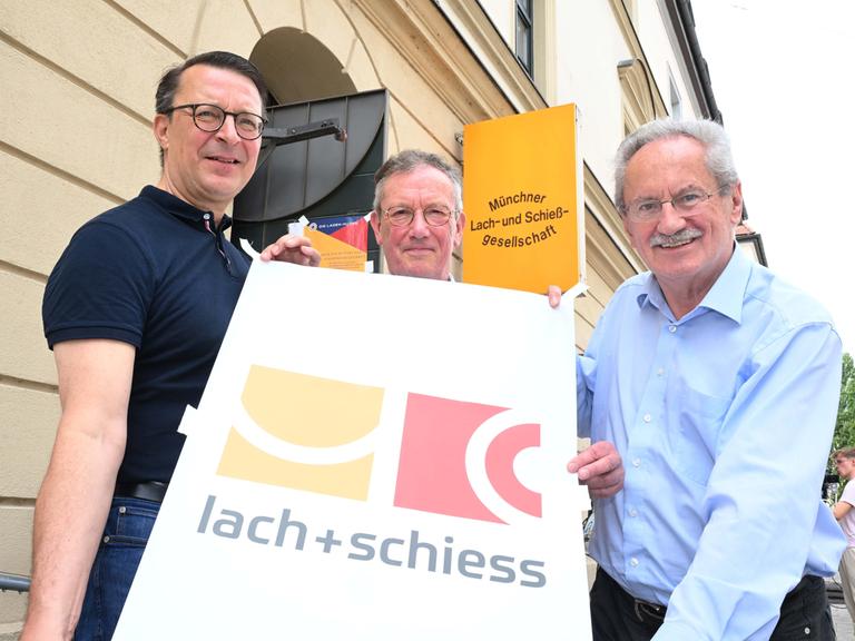 Die Interimsgeschäftsführer Christian Schultz (links) und Ulrich Spandau (Mitte) sowie Gesellschafter Christian Ude (rechts) präsentieren am 12. Juli 2023 in München das neue Logo der Lach- und Schießgesellschaft.
