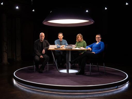 Christian Berkel, Xaver von Cranach, Marlene Knobloch und Thea Dorn sitzen an einem Tisch im Fernsehstudio und schauen in die Kamera.
