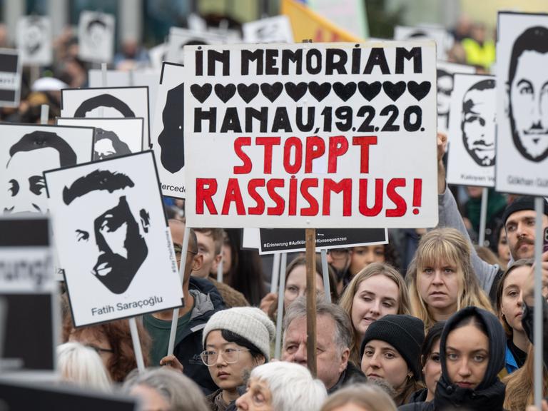 Mehrere tausend Menschen versammeln sich nach einem Gedenkmarsch anlässlich des vierten Jahrestages des rassistische Anschlags von Hanau auf dem Marktplatz in der Innenstadt. Viele Teilnehmer halten dabei Schilder und Bilder der Opfer hoch.