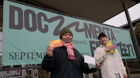 Reza Afisina (links) vom Kuratorenkollektiv Ruangrupa und Leon Schniewind, Inhouse Desinger bei der documenta, stehen mit Grußkarten bei der Vorstellung des neuen Logo der documenta fifteen.