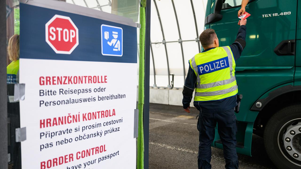 Ein Bundespolizist kontrolliert an der deutsch-tschechischen Grenze den Grenzverkehr, aus einem Lastwagen werden Dokumente zu ihm heruntergereicht.