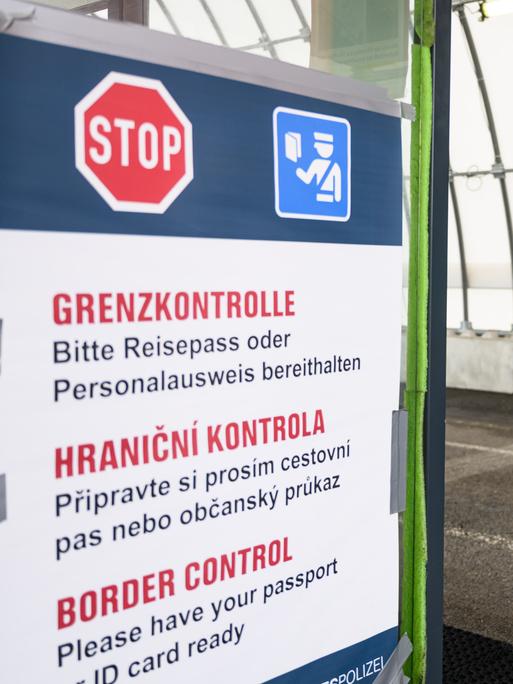 Ein Bundespolizist kontrolliert an der deutsch-tschechischen Grenze den Grenzverkehr, aus einem Lastwagen werden Dokumente zu ihm heruntergereicht.
