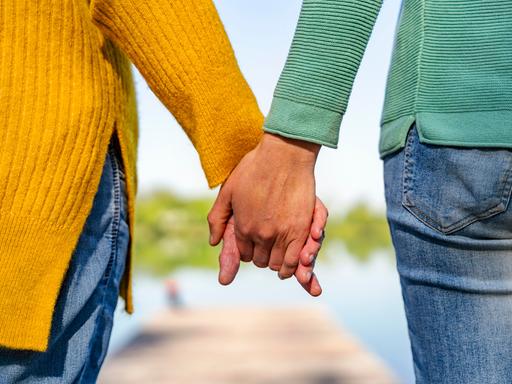 Zwei Personen halten sich an den Händen. 