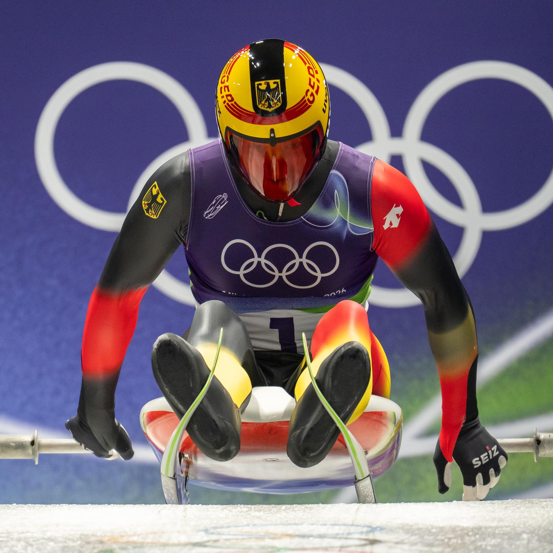 Der Rodler Max Langenhan sitzt auf seinem Schlitten beim Start und stößt sich mit den Händen ab.