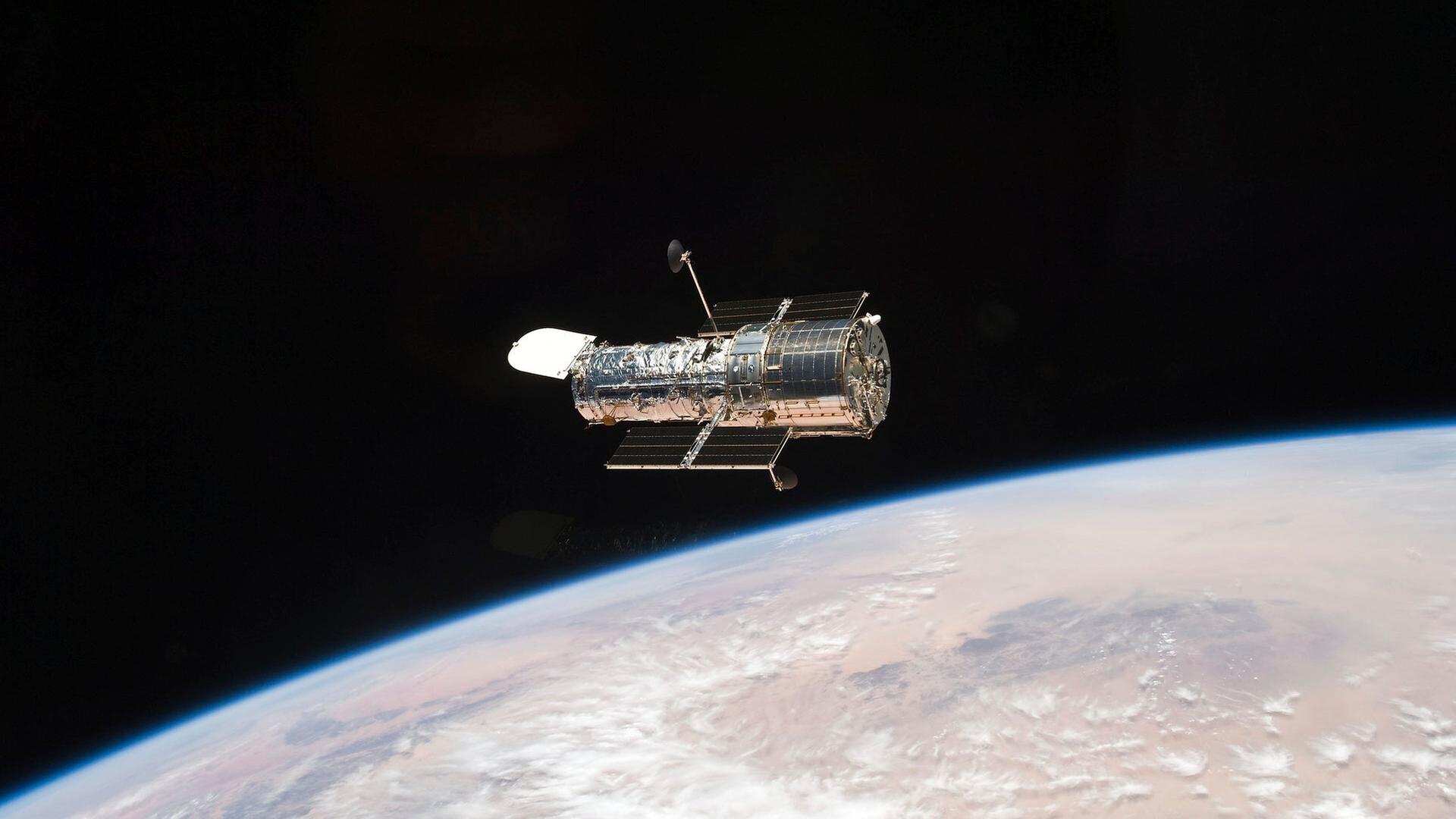 Das Weltraumteleskop Hubble im Weltraum über einem Planeten.