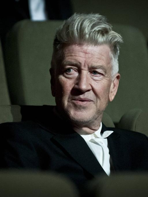 Ein Foto mit starker Filmkörnung zeigt David Lynch auf einem Kinositz.