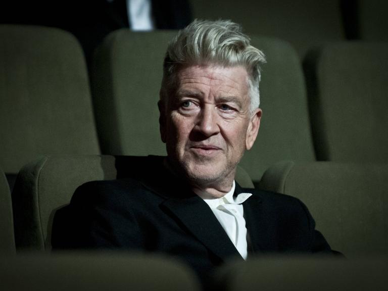 Ein Foto mit starker Filmkörnung zeigt David Lynch auf einem Kinositz.