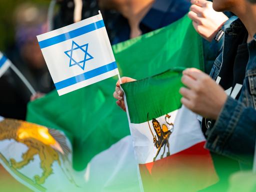 Eine Frau hält eine israelische und eine iranische Fahne während einer Kundgebung auf der Wiese gegenüber des iranischen Konsulats. Erstmals in der Geschichte der Islamischen Republik hatte der Iran seinen Erzfeind Israel in der Nacht direkt angegriffen.