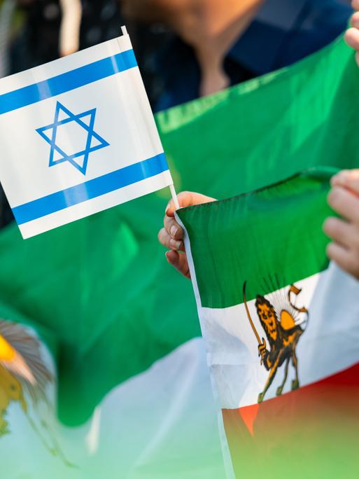 Eine Frau hält eine israelische und eine iranische Fahne während einer Kundgebung auf der Wiese gegenüber des iranischen Konsulats. Erstmals in der Geschichte der Islamischen Republik hatte der Iran seinen Erzfeind Israel in der Nacht direkt angegriffen.