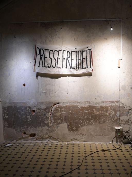 Auf einer Wand ist ein Banner aufgehängt mit der Aufschrift "PRESSEFREIHEIT".