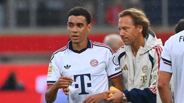 Jamal Musiala wirkt nach seiner Ohnmacht benommen. Ein Arzt von Bayern München begleitet ihn vom Spiel-Feld.