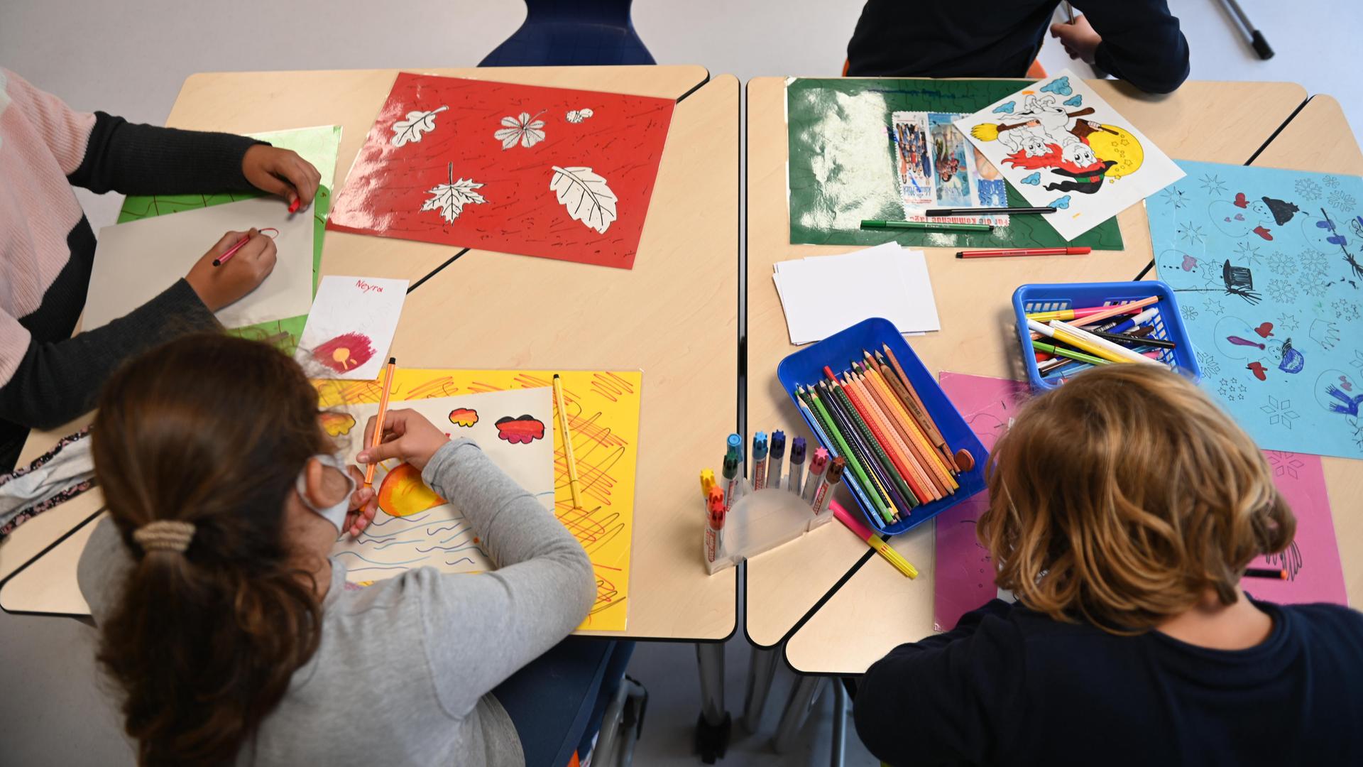 Kinder von hinten. Sie sitzen an einem Tisch und malen in einer Ganztagsschule in Berg am Laim. Kinder von hinten. Sie sitzen an einem Tisch und malen in einer Ganztagsschule in Berg am Laim.