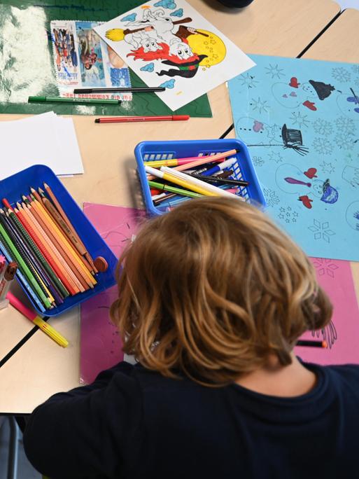 Kinder von hinten. Sie sitzen an einem Tisch und malen in einer Ganztagsschule in Berg am Laim.