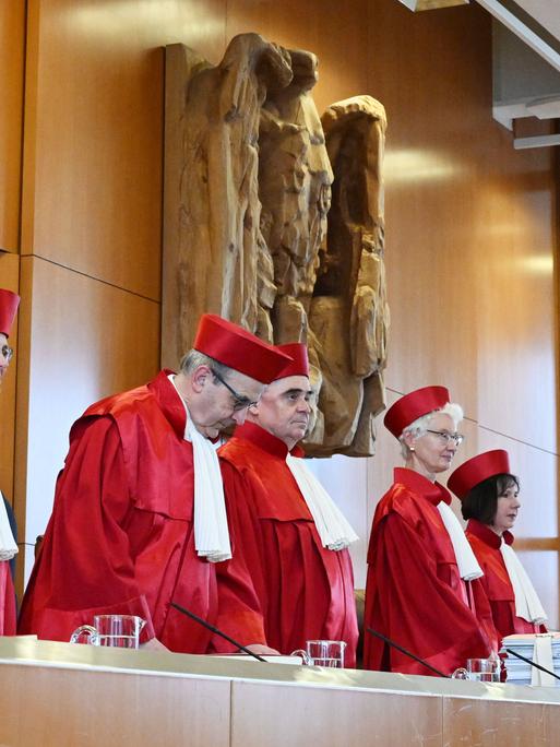 Mehrere Richter stehend in roter Robe. Hinter ihnen eine Wand mit einer steinernen Skulptur. Mehrere Richter stehend in roter Robe. Hinter ihnen eine Wand mit einer steinernen Skulptur.