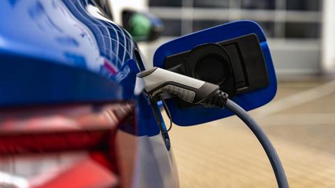 Nahaufnahme eine Tankklappe eines E-Autos, welches gerade geladen wird.
