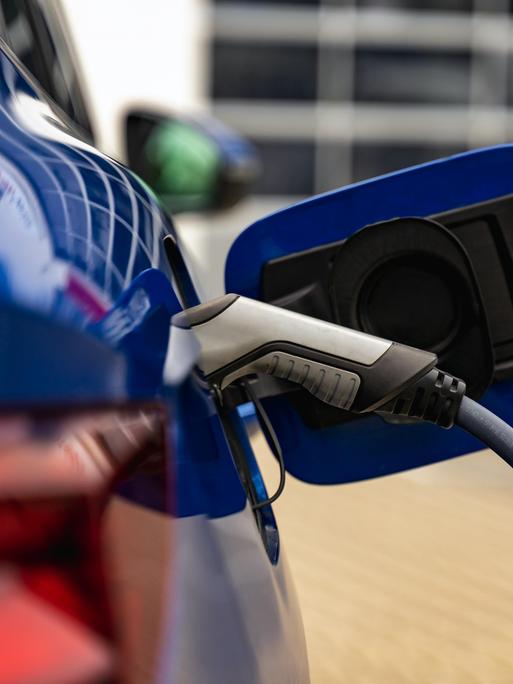 Nahaufnahme eine Tankklappe eines E-Autos, welches gerade geladen wird.