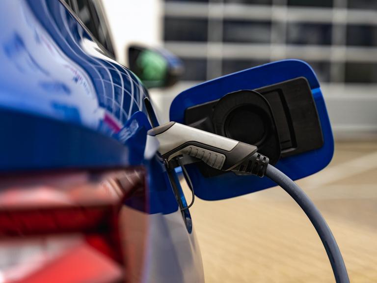 Nahaufnahme eine Tankklappe eines E-Autos, welches gerade geladen wird.