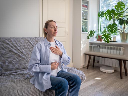 Eine Frau praktiziert Selbsthilfetechniken zum Stressabbau und zur Tiefenatmung.