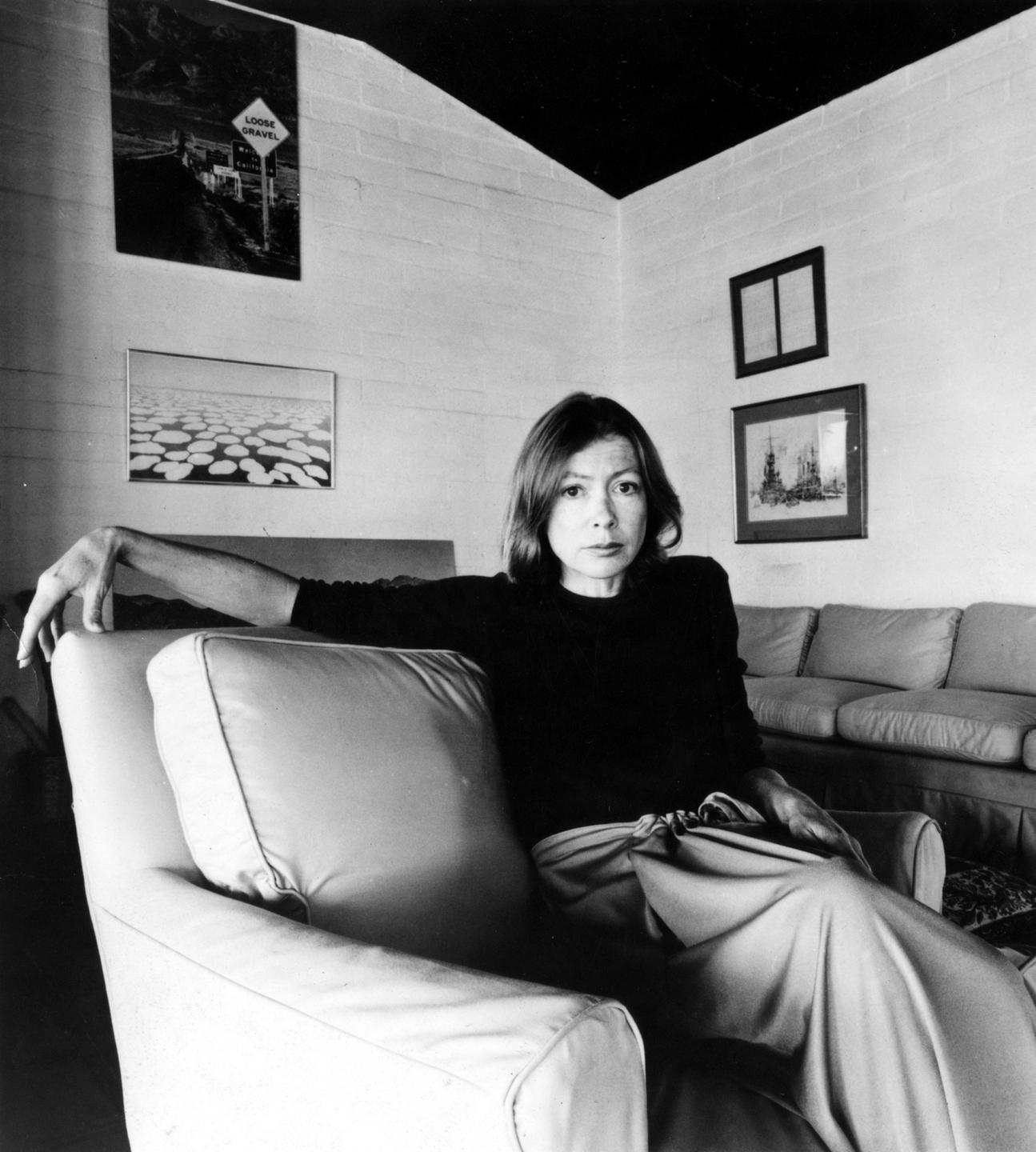 Schwarzweißaufnahme: Joan Didion in legerer Pose auf einem Sofa.