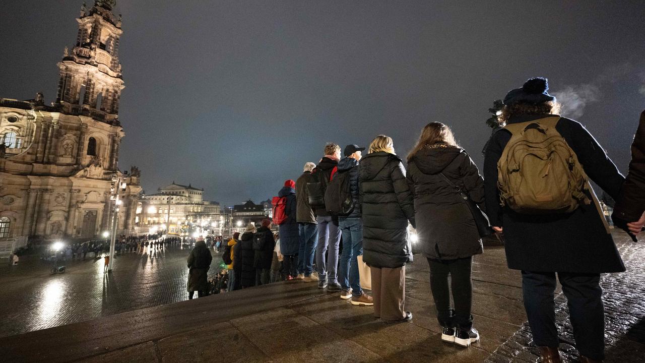 Zahlreiche Menschen stehen nebeneinander vor der Katholischen Hofkirche in Dresden und bilden eine Menschenkette. 