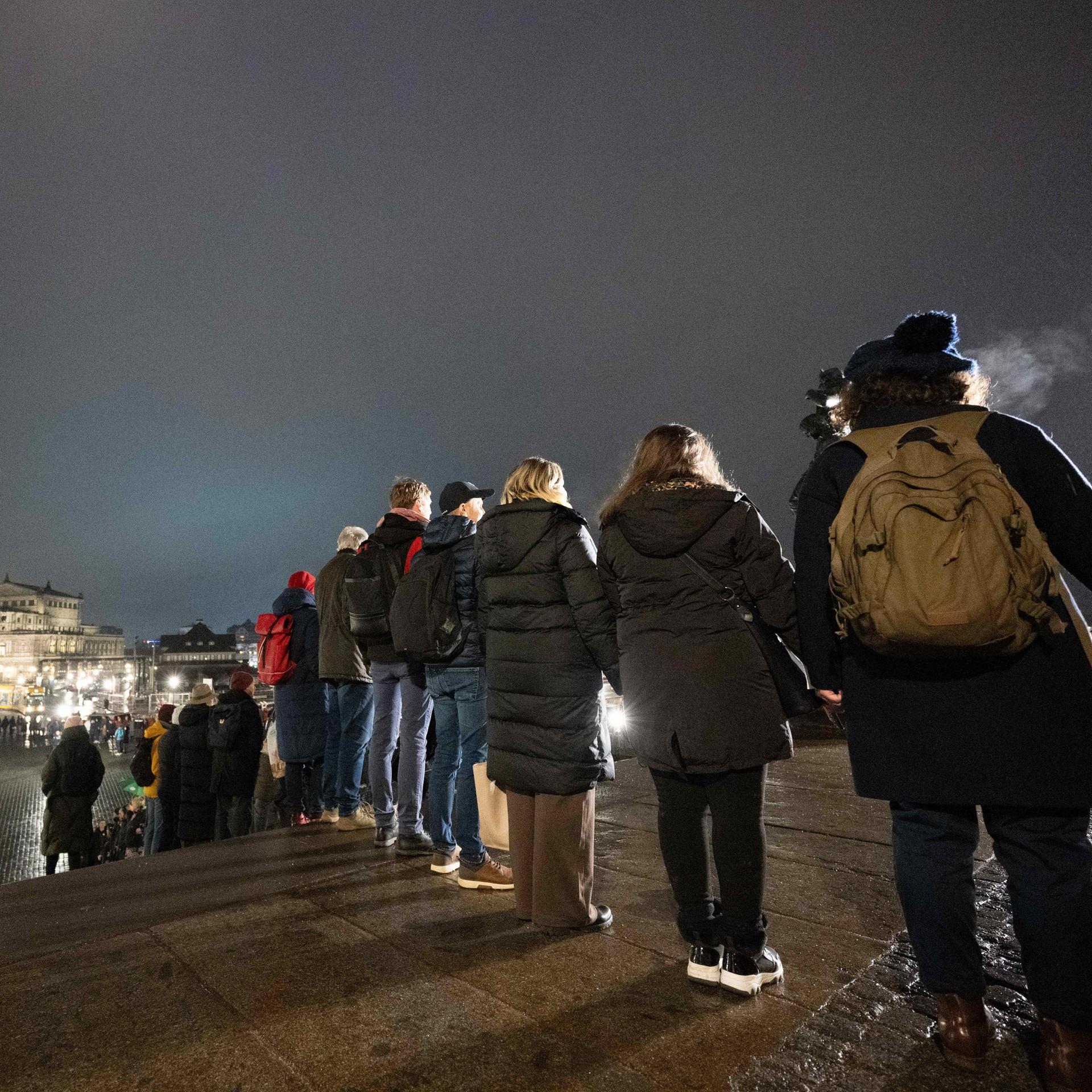 Zahlreiche Menschen stehen nebeneinander vor der Katholischen Hofkirche in Dresden und bilden eine Menschenkette. 