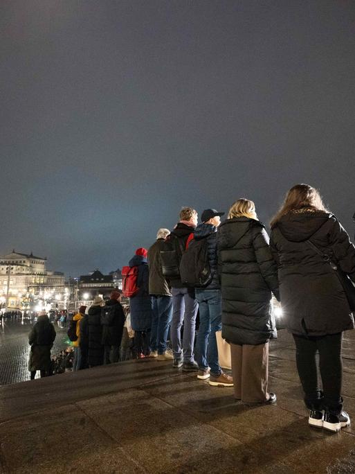 Zahlreiche Menschen stehen nebeneinander vor der Katholischen Hofkirche in Dresden und bilden eine Menschenkette. 