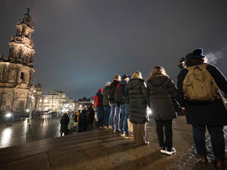 Zahlreiche Menschen stehen nebeneinander vor der Katholischen Hofkirche in Dresden und bilden eine Menschenkette. 