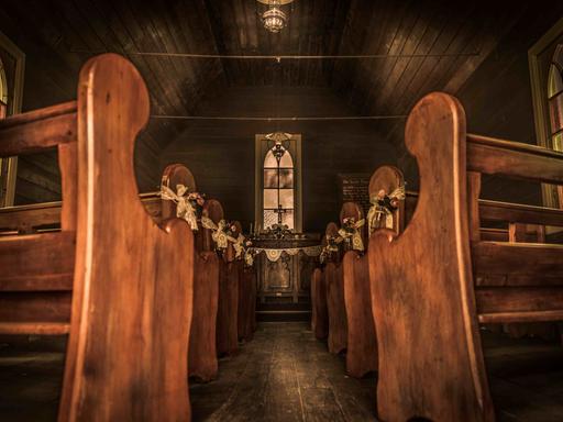 Blick entlang des leeren Gangs einer hölzernen Siedlerkirche zum Altar.