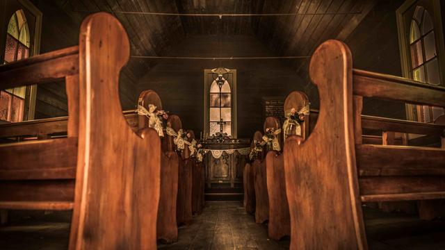 Blick entlang des leeren Gangs einer hölzernen Siedlerkirche zum Altar.